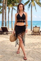 Woman in a black beach outfit with palm trees and ocean in the background