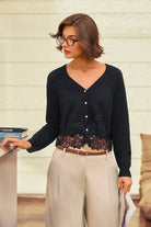 A woman wearing a black long-sleeve cardigan with a lace hem detail, paired with beige wide-leg trousers and glasses, standing in an indoor setting.