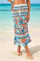 Person wearing a colorful floral skirt on a beach