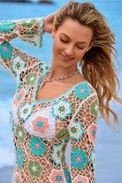 Woman wearing a colorful crochet cover-up with a blue sky background