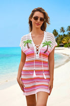 Woman wearing a colorful striped cover-up with palm tree designs on a beach.
