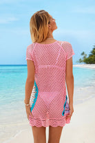 Woman wearing a pink crochet cover-up on a beach