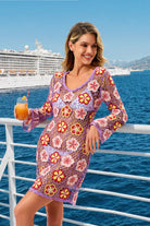 Woman in a colorful dress standing on a cruise ship deck with a scenic ocean view.