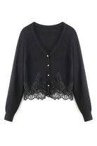 A black long-sleeve cardigan featuring a V-neckline, button-front closure, and an intricate black lace trim along the hem and cuffs, displayed against a solid white background.
