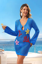 Woman in a blue dress with starfish and coral designs, holding a drink on a boat.