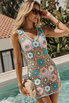A woman wearing a sleeveless crochet mini dress with a multicolor floral pattern in teal, pink, and green over a white base, standing by a swimming pool.