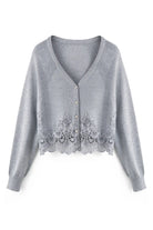A light gray knit cardigan with a V-neck, button closure, and a decorative lace panel along the hem, shown on a plain white background.