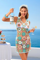 Woman in a floral dress holding a bottle and glass by the ocean