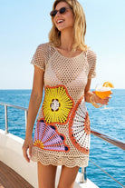 Woman on a boat holding a drink, wearing a colorful crochet cover-up.