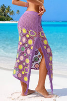 Side view of twilight purple crochet maxi skirt showing fringe high side slit and colorful floral crochet pattern, worn on sandy beach with palm trees