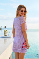 Woman in a purple crochet dress standing by a pool with a scenic background